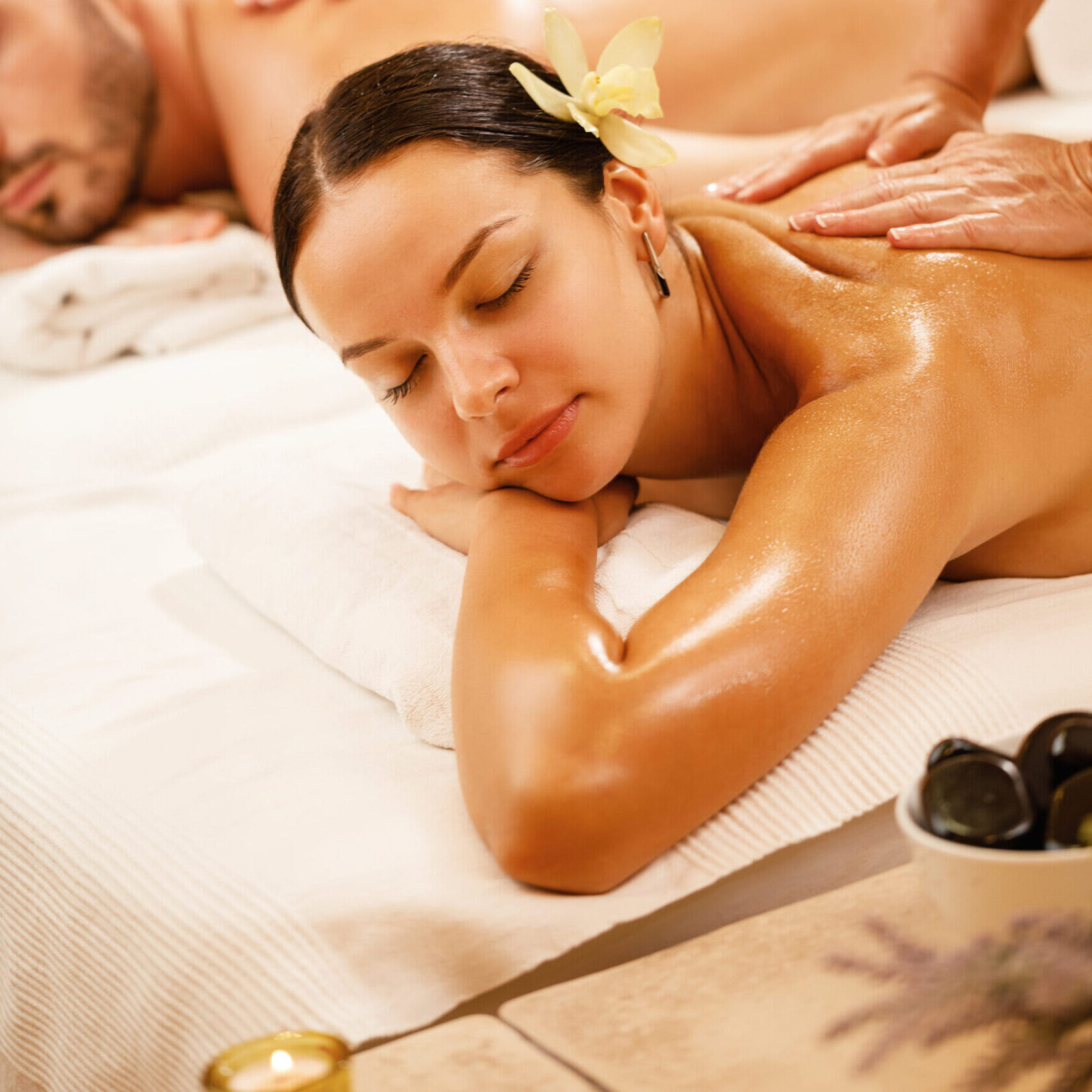 Young couple relaxing during back massage at health spa. Focus is on young woman.